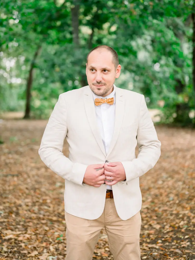 The groom buttoning his linen jacket among the trees of the Parc de Cazalet