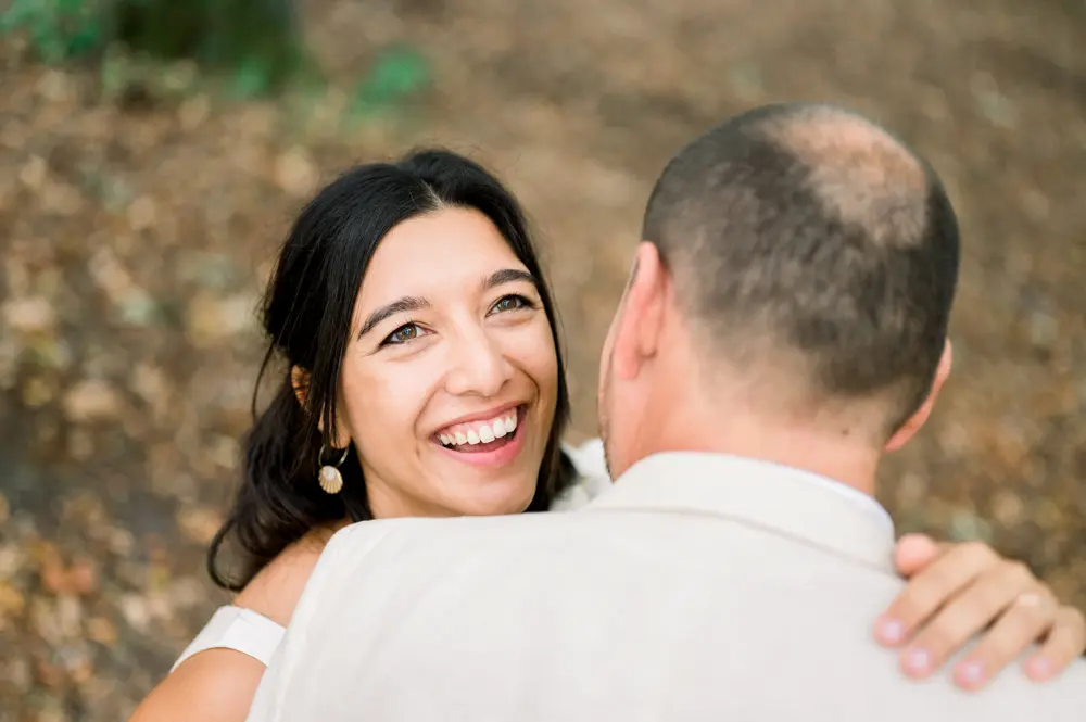 The bride laughing heartily in the arms of the groom, seen from behind