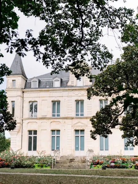 Façade of Château de Cazalet in Pessac framed by the park's branches