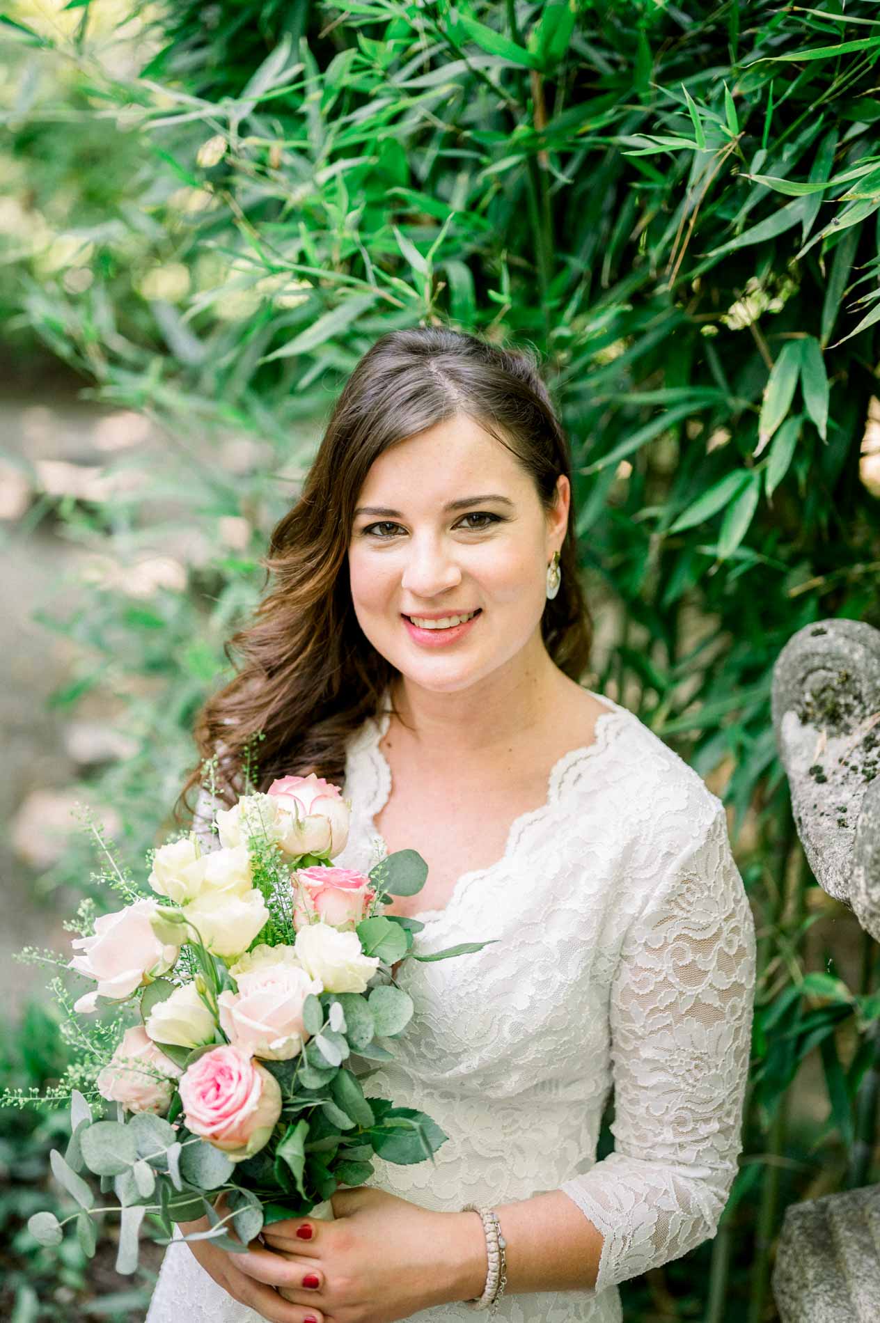 Smiling mother-to-be holding a pink rose bouquet among bamboo