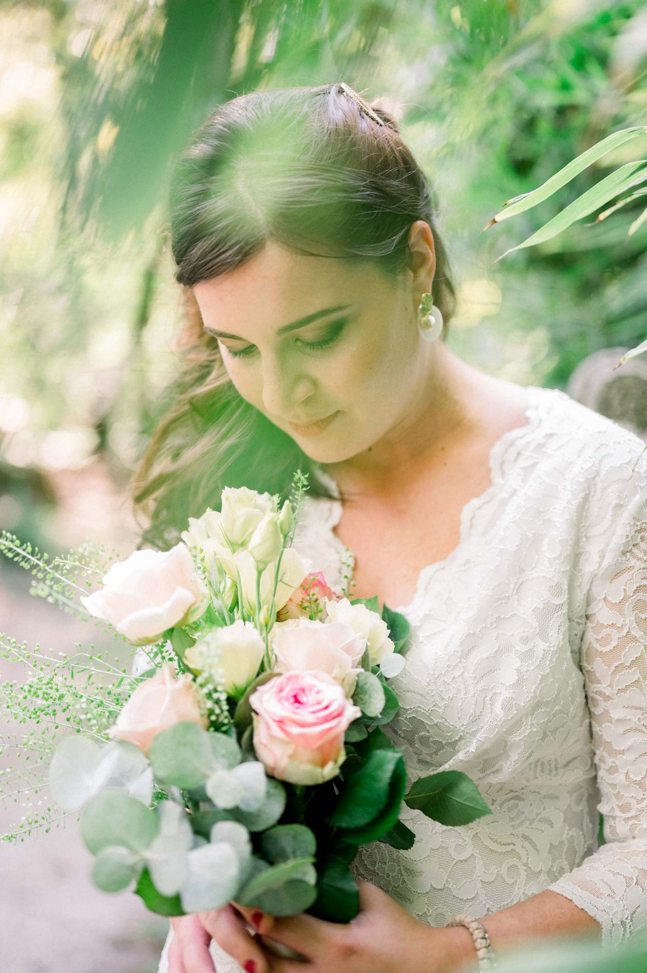 Mother-to-be looking down at her bouquet of roses and eucalyptus
