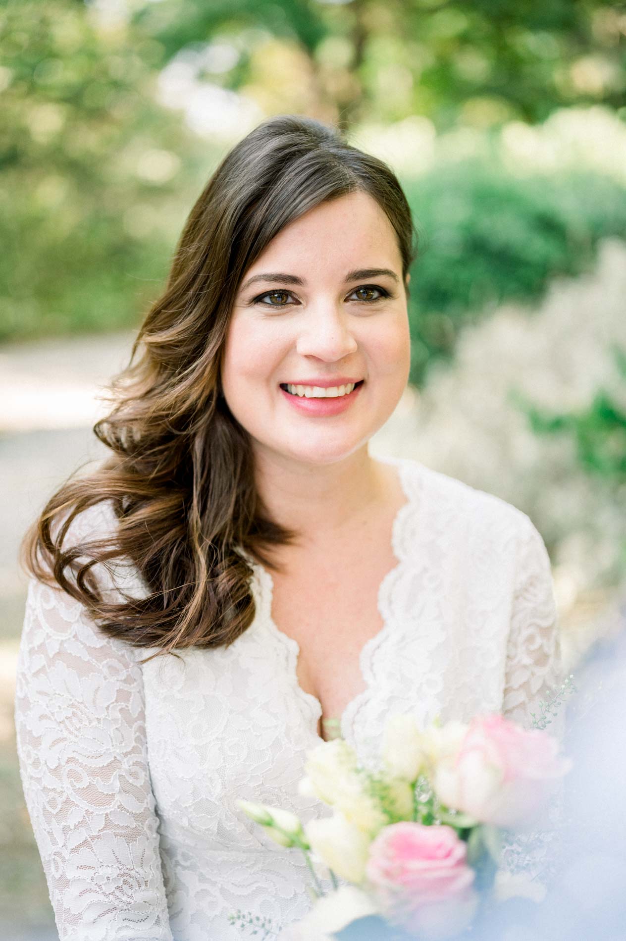 Smiling portrait of the curly-haired mother-to-be in a lace dress