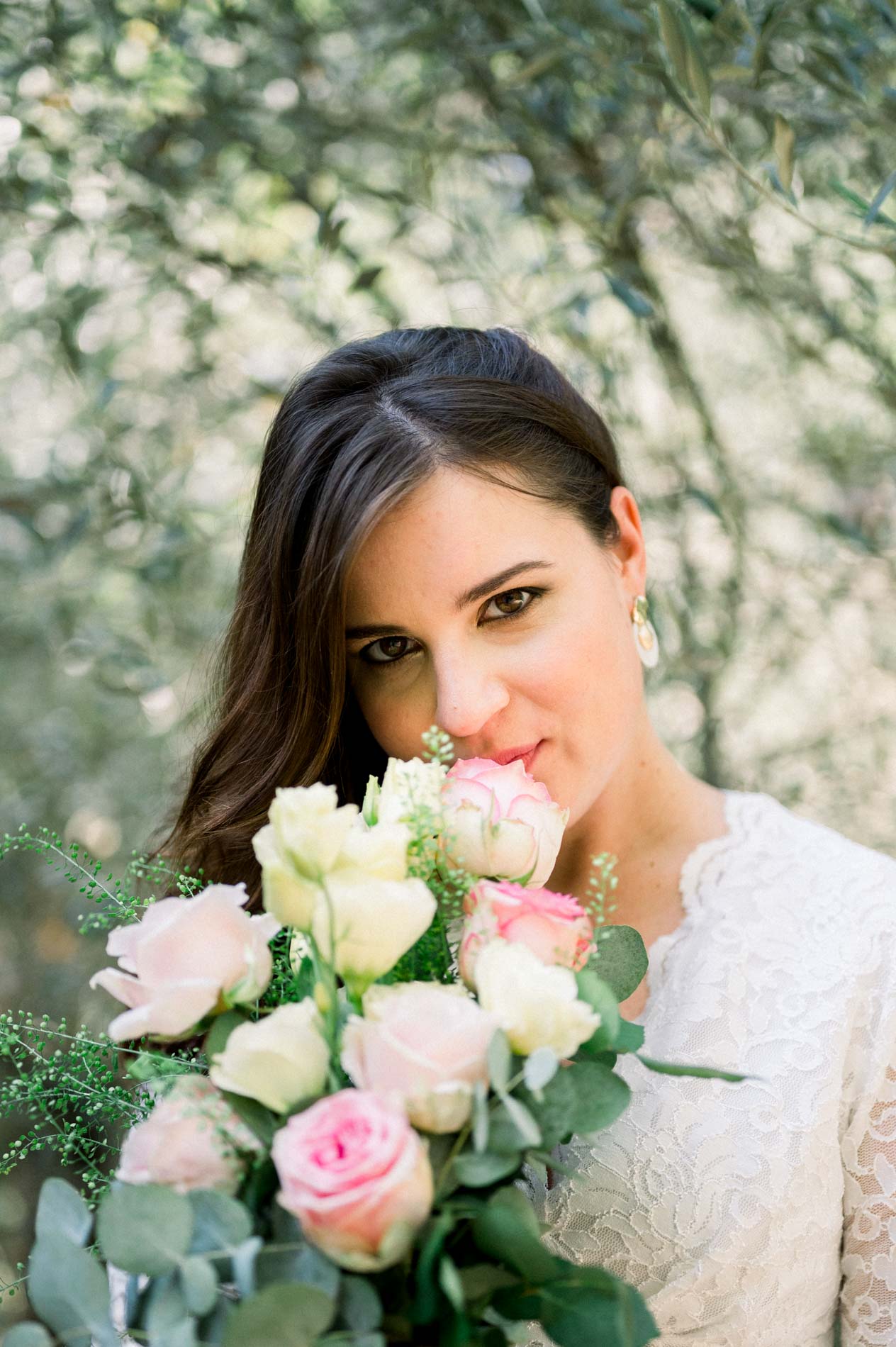 Mother-to-be smelling her rose bouquet under the olive trees