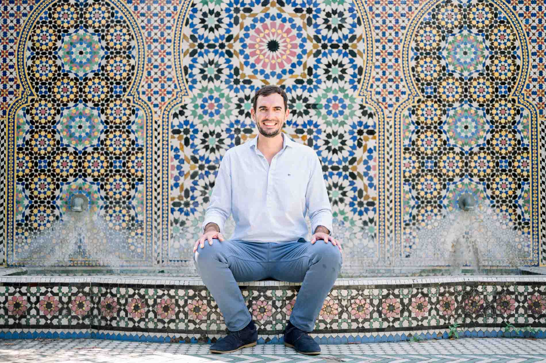 Father-to-be sitting in front of a colourful Moroccan zellige fountain