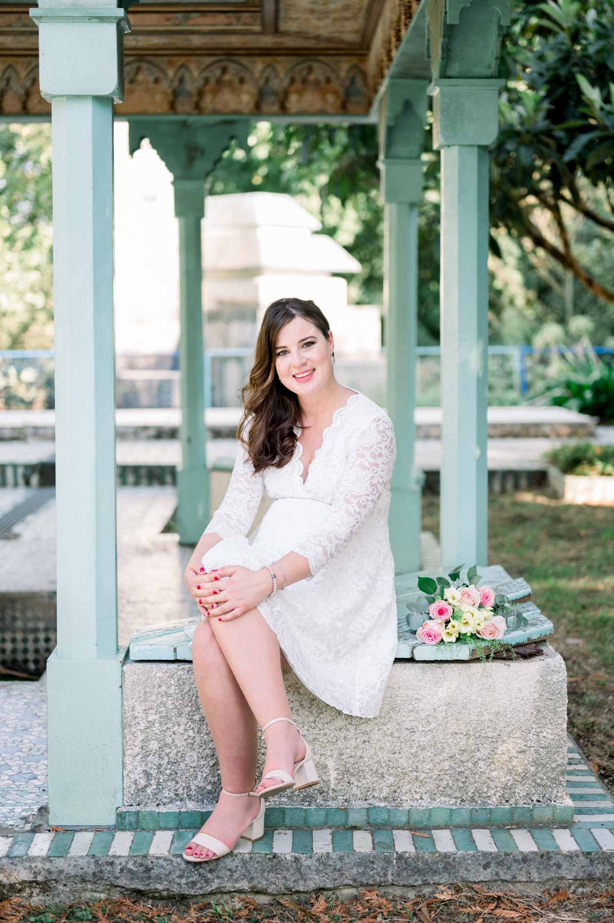 Mother-to-be sitting beneath a pavilion with pale green columns