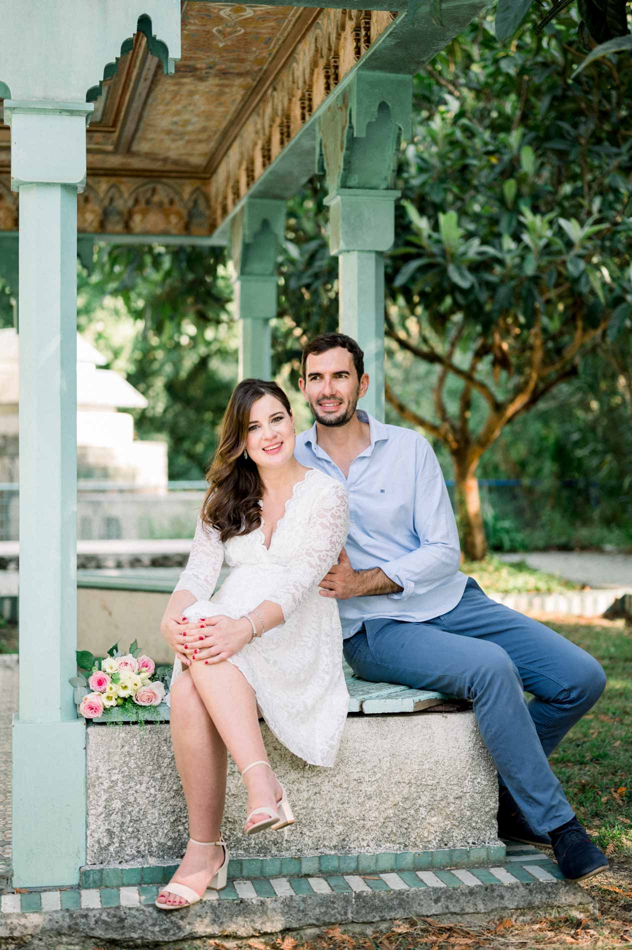 Couple sitting side by side under the pavilion, bouquet beside them