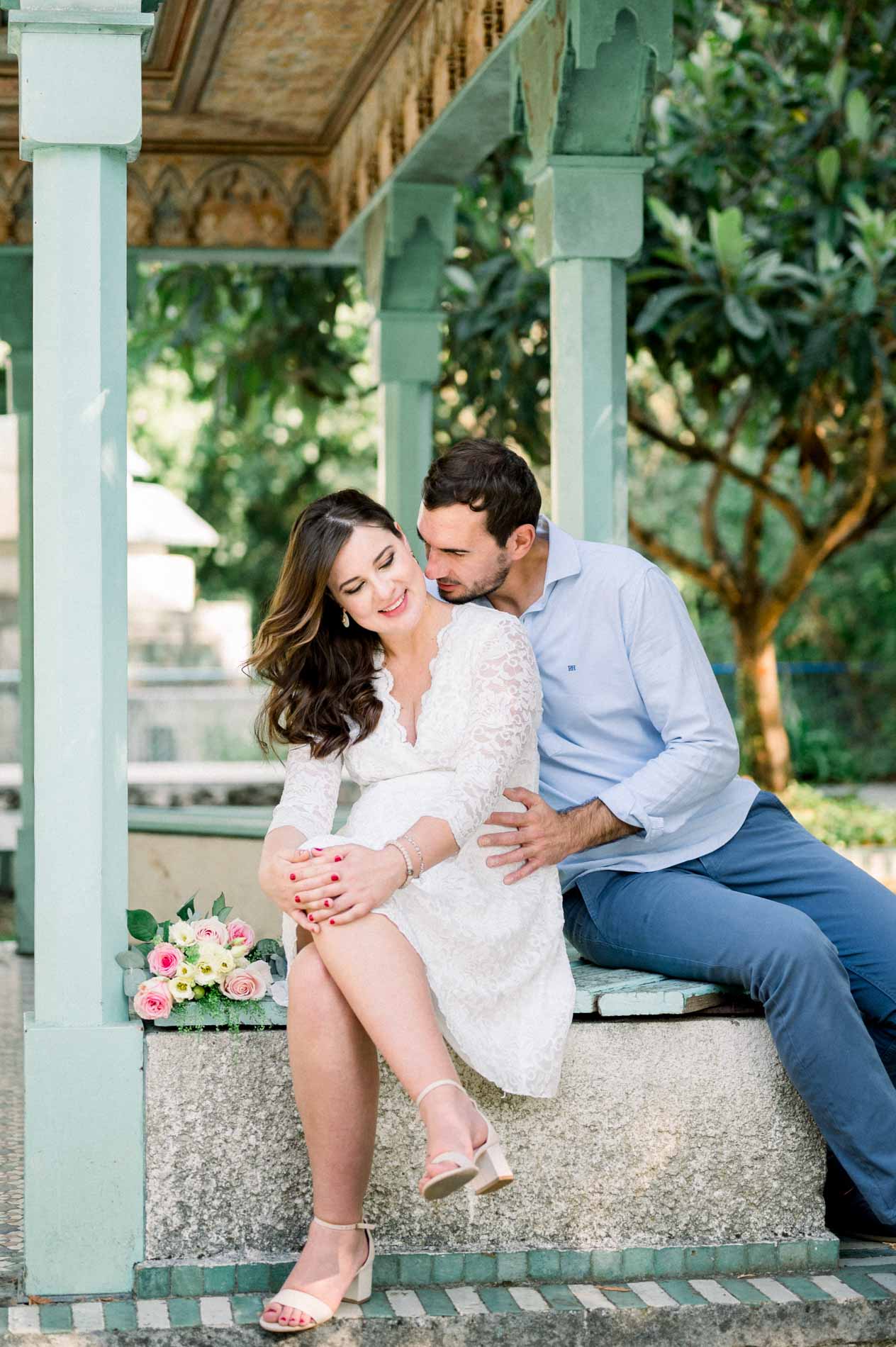 Father-to-be kissing his pregnant partner's temple under the pavilion