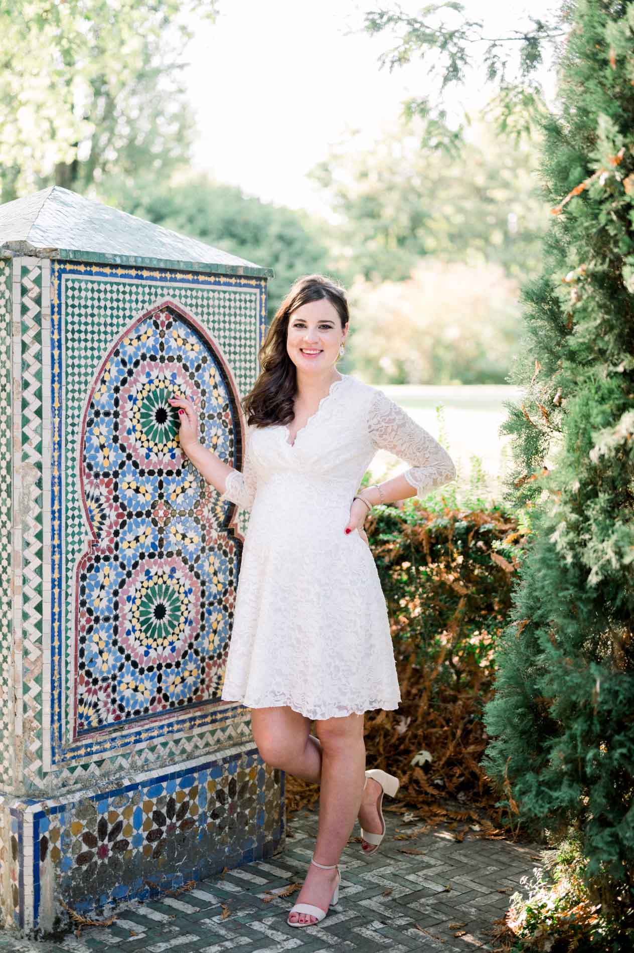 Mother-to-be leaning on a zellige fountain, hand on her bump