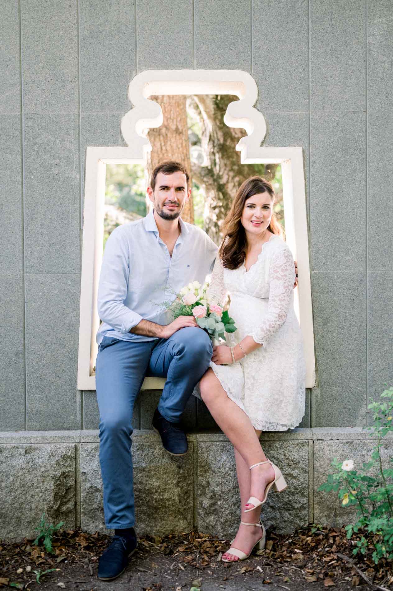 Couple sitting in the frame of a decorative opening in a grey wall