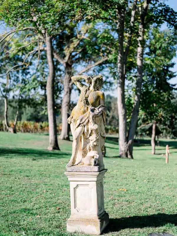 Stone statue on a pedestal in the shaded park of Château de Garde