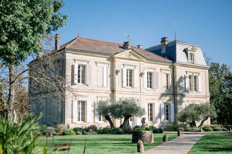 Château de Garde façade with olive trees under a clear blue sky