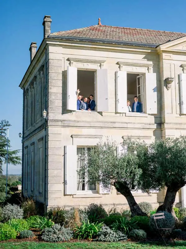 Bride and groom leaning out of the upstairs windows of Château de Garde