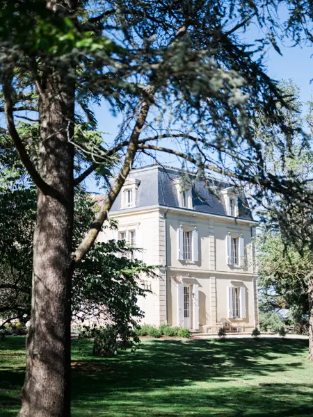 Château de Garde glimpsed between the tall trees of its park