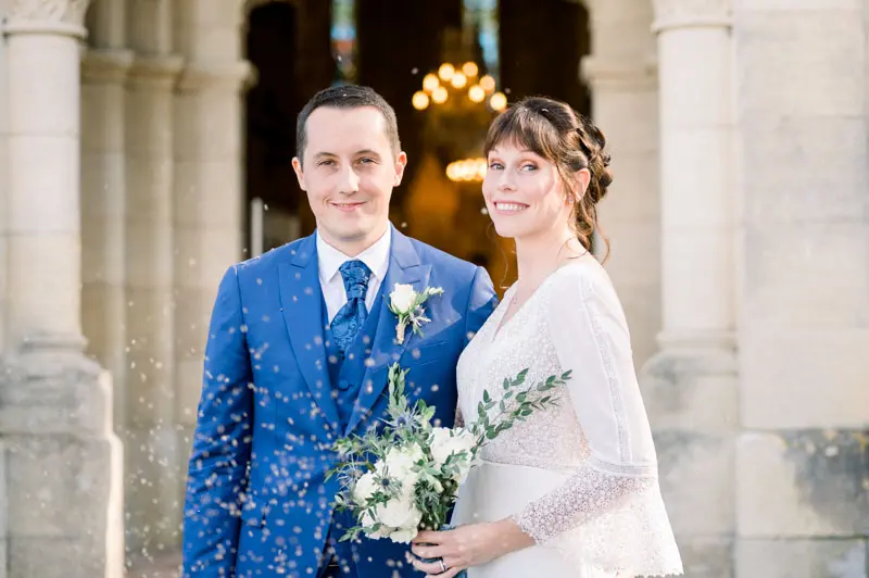 Smiling newlyweds under a shower of petals at Notre-Dame de Cabara church