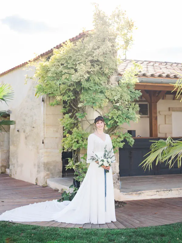 Bride with her bouquet beneath wisteria in a Bordeaux château courtyard