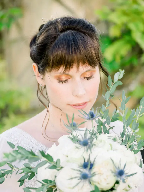 Close-up of the bride and her bouquet of white roses and blue thistles