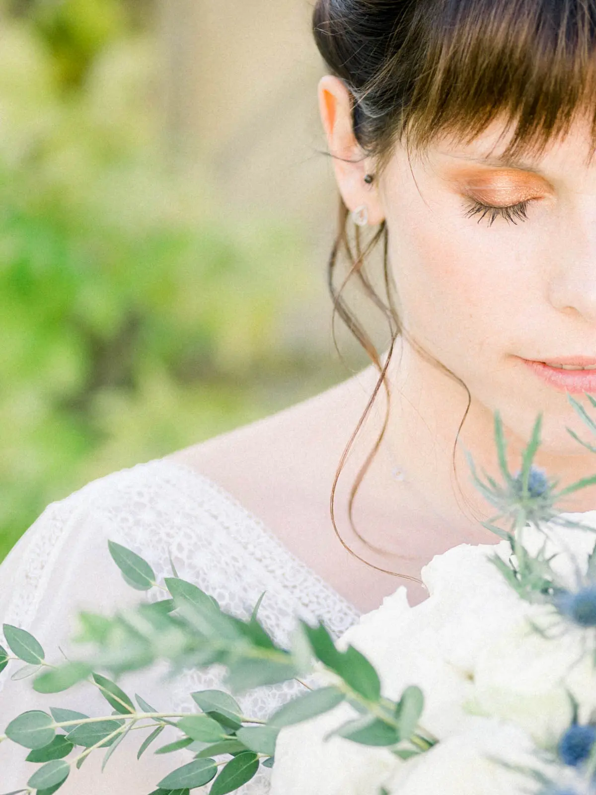 Profile of the bride with closed eyes, golden makeup and bouquet in the foreground
