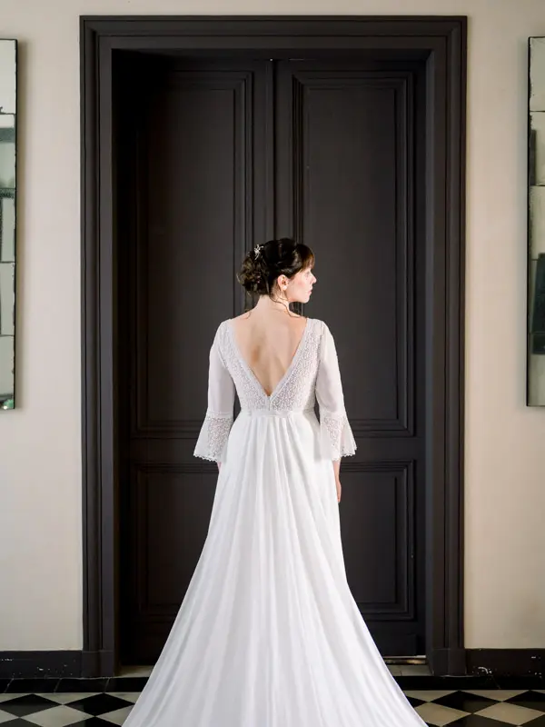 Bride seen from behind in front of a black door, V-back wedding dress