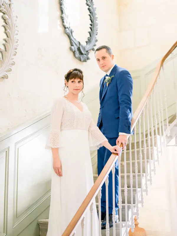 Bride and groom posing on the wooden-railed staircase of Château de Garde