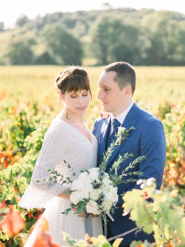Bride and groom embracing among autumn-coloured vines near Château de Garde