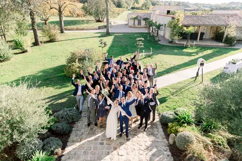 Group photo of wedding guests raising their arms, taken from above in the garden