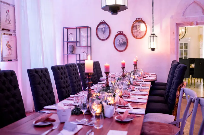 Dinner tables in pink light with candlesticks and tufted chairs