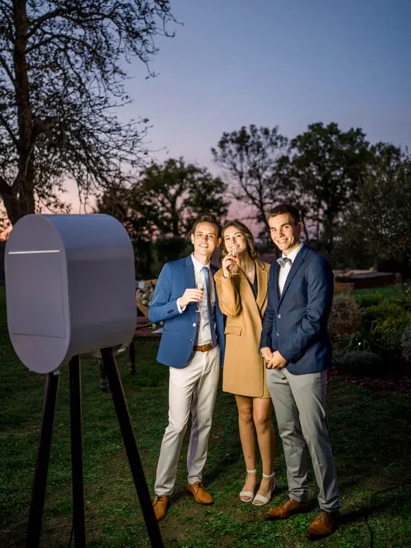 Guests posing in front of the photo booth in the garden at dusk