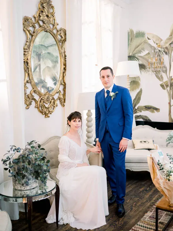 Bride and groom posing in a salon with a large gilded mirror