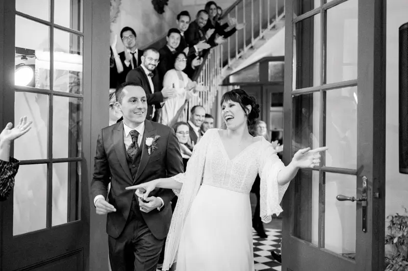 Bride and groom making a joyful entrance into the dining room, in black and white