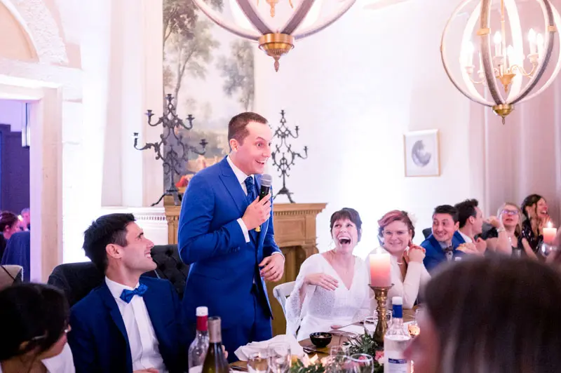 Groom giving a speech into the microphone before seated guests