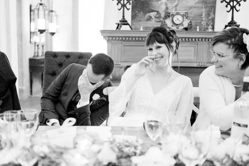 Bride bursting into laughter during the speeches, in black and white