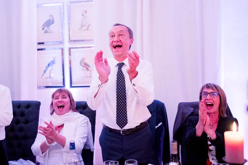 Guests applauding enthusiastically during the wedding reception
