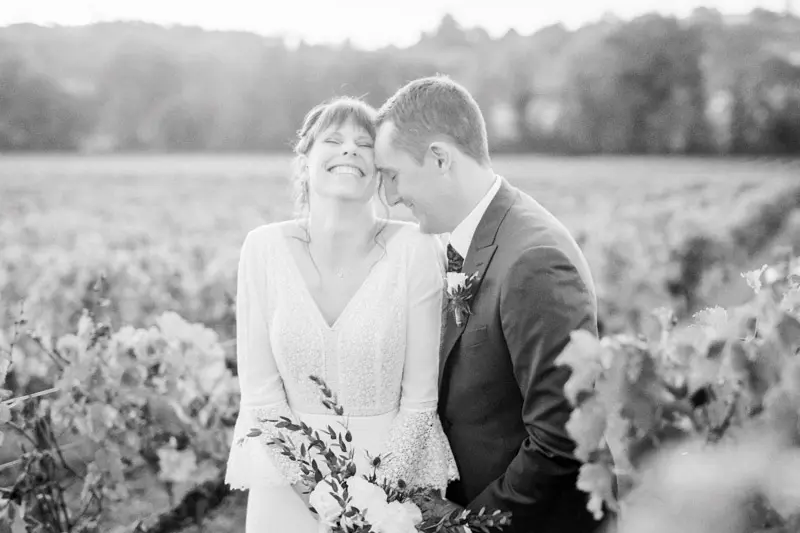 Bride and groom laughing cheek to cheek in the vineyard, in black and white