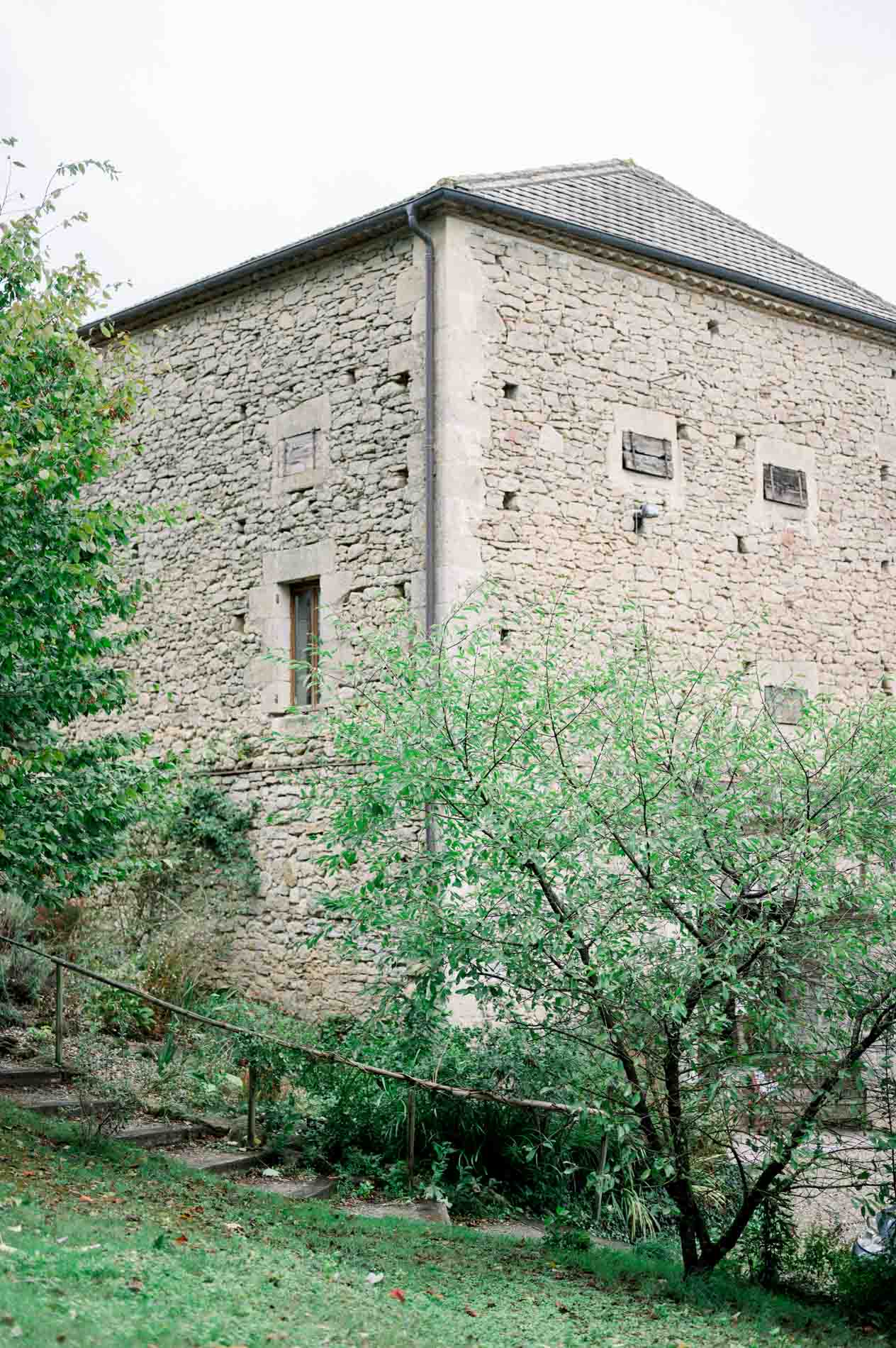 Old stone farm building surrounded by greenery at Ferme du Moulinat
