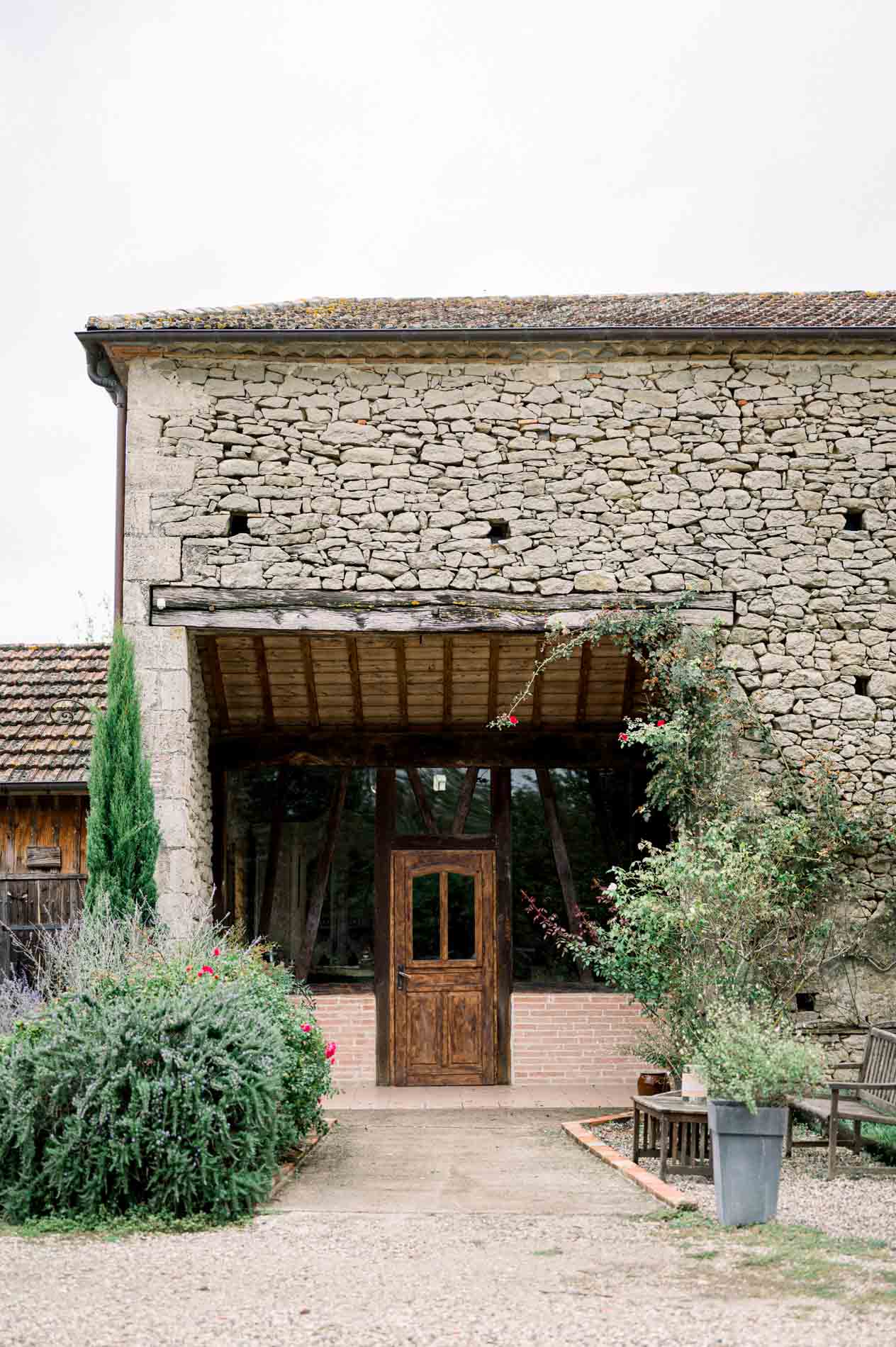 Stone barn with a wooden door and porch at Ferme du Moulinat