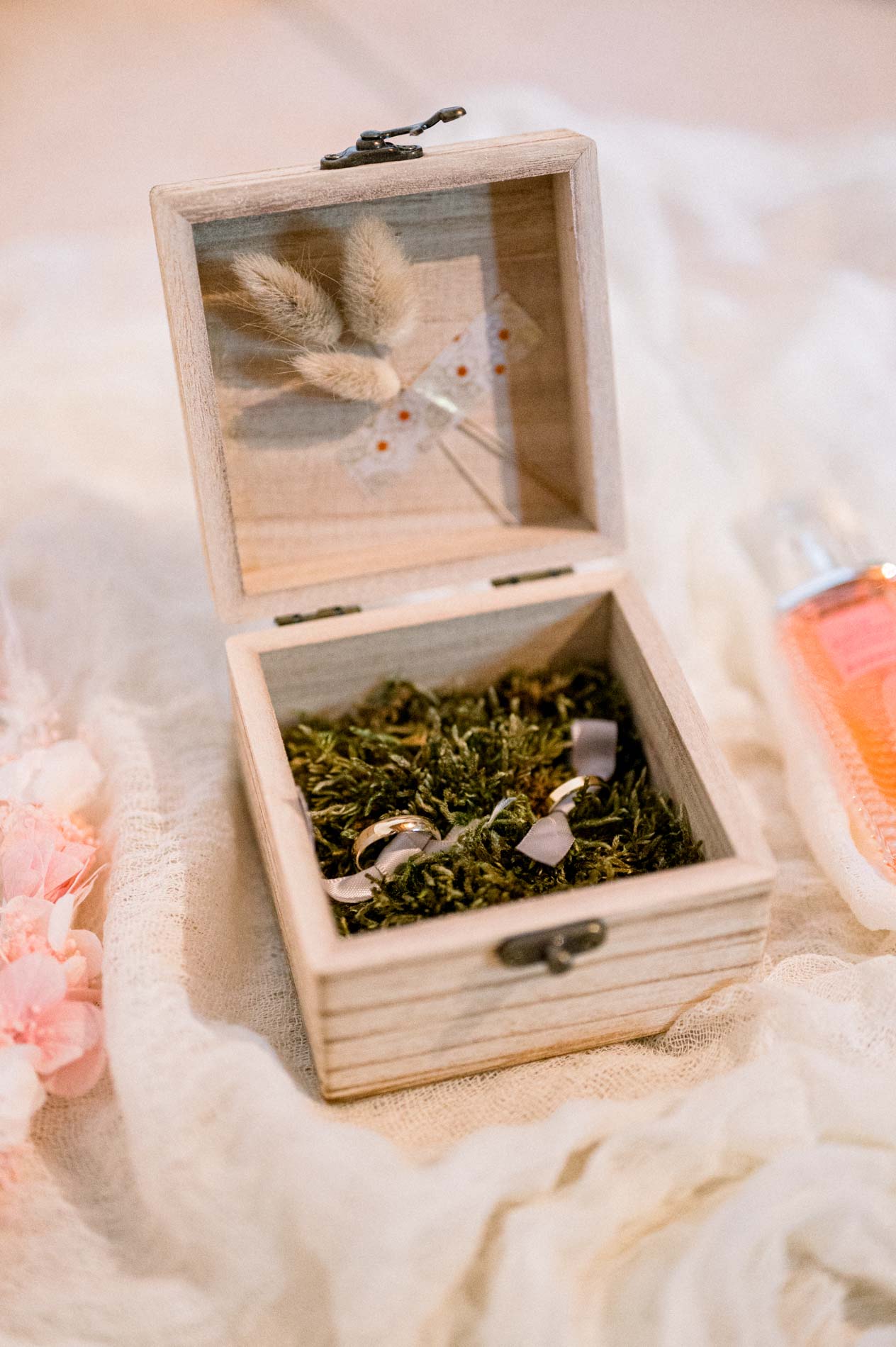 Wooden ring box lined with moss resting on a white sheet