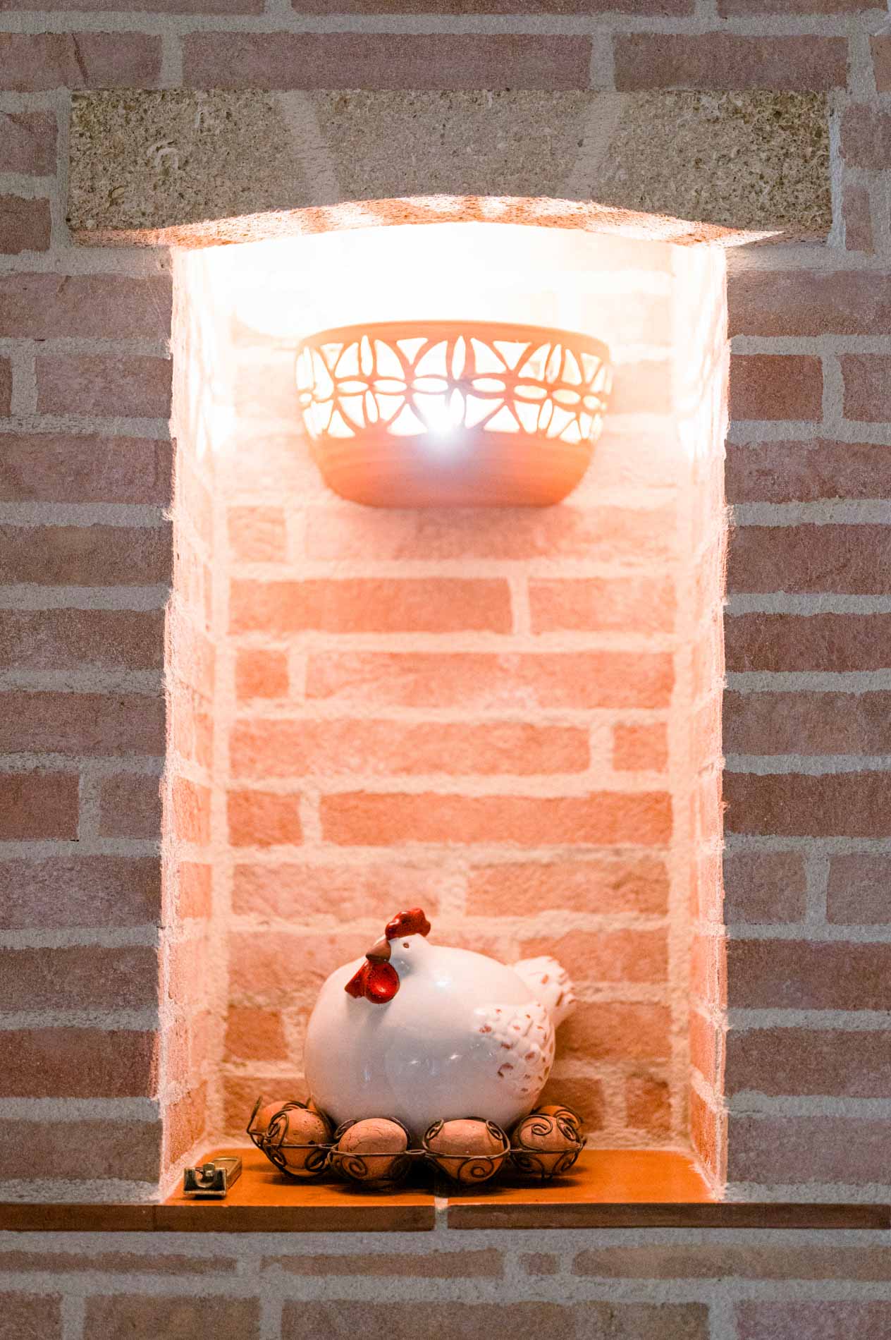 Lit brick niche with a decorative hen and walnuts