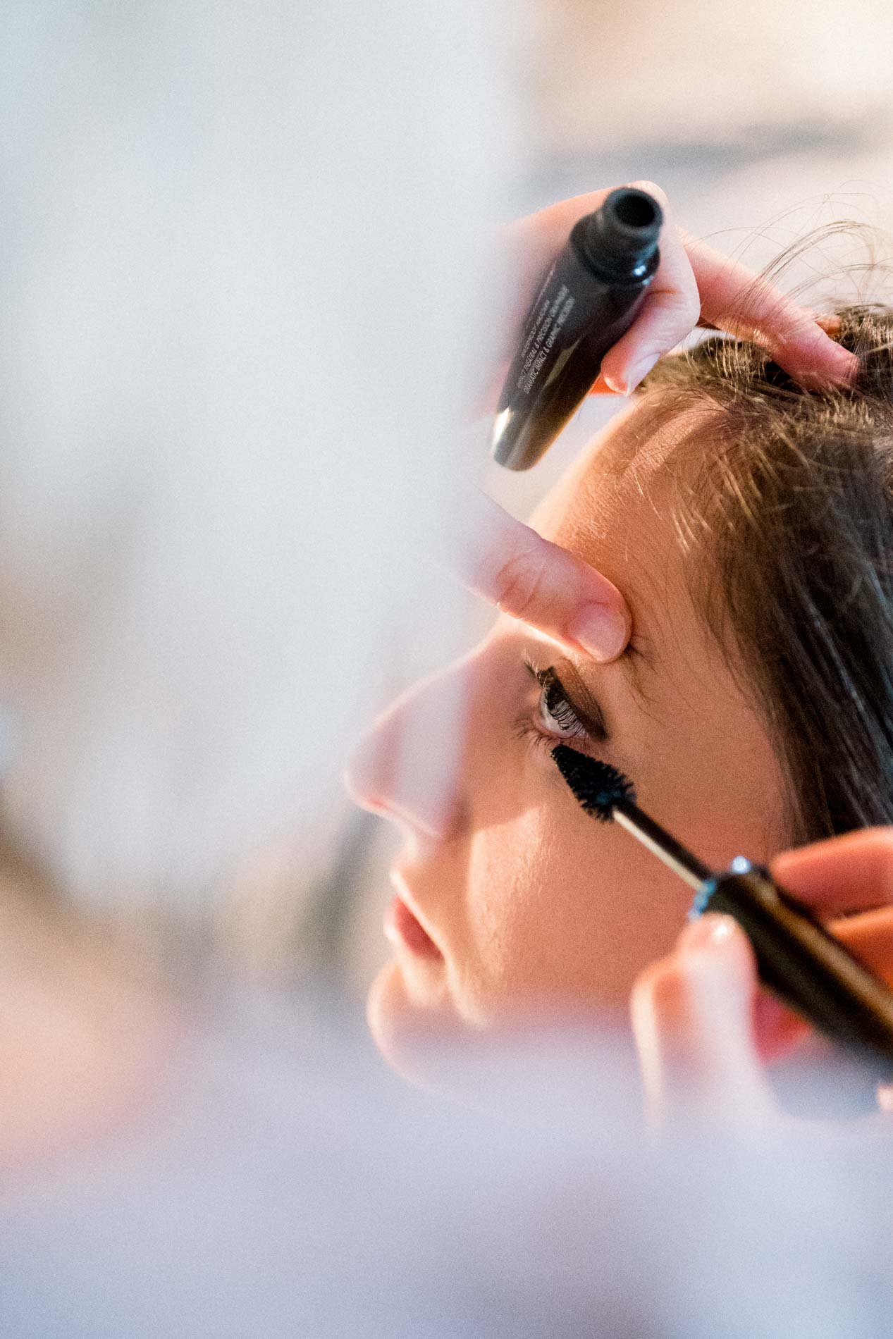 Bride having mascara applied while getting ready