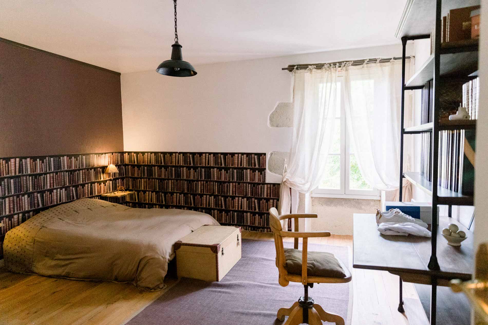 Bedroom at Ferme du Moulinat with a wall of books and a large bed