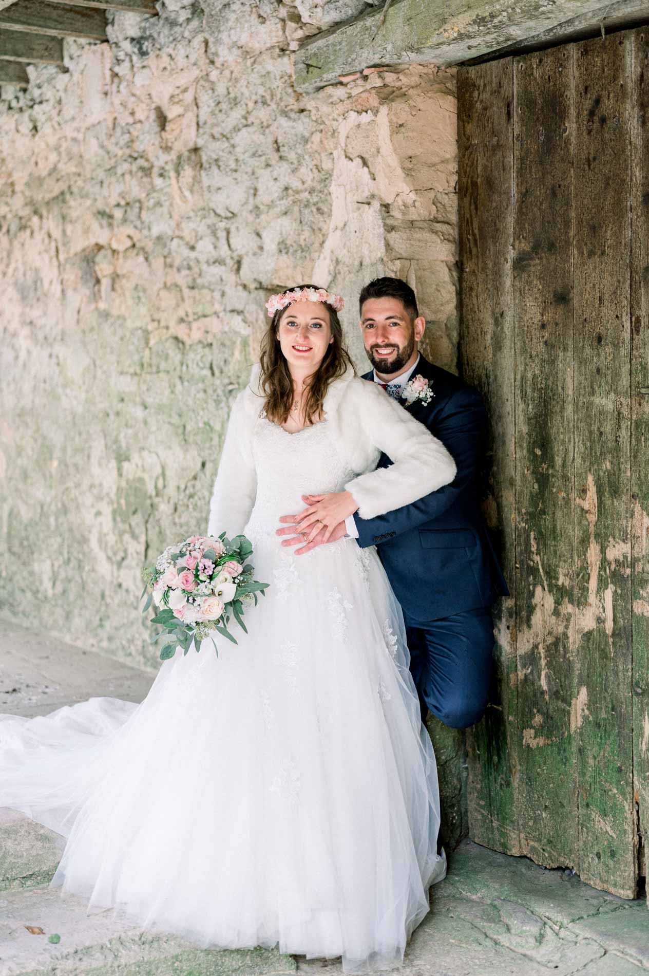 Bride leaning into the groom against the wooden barn door