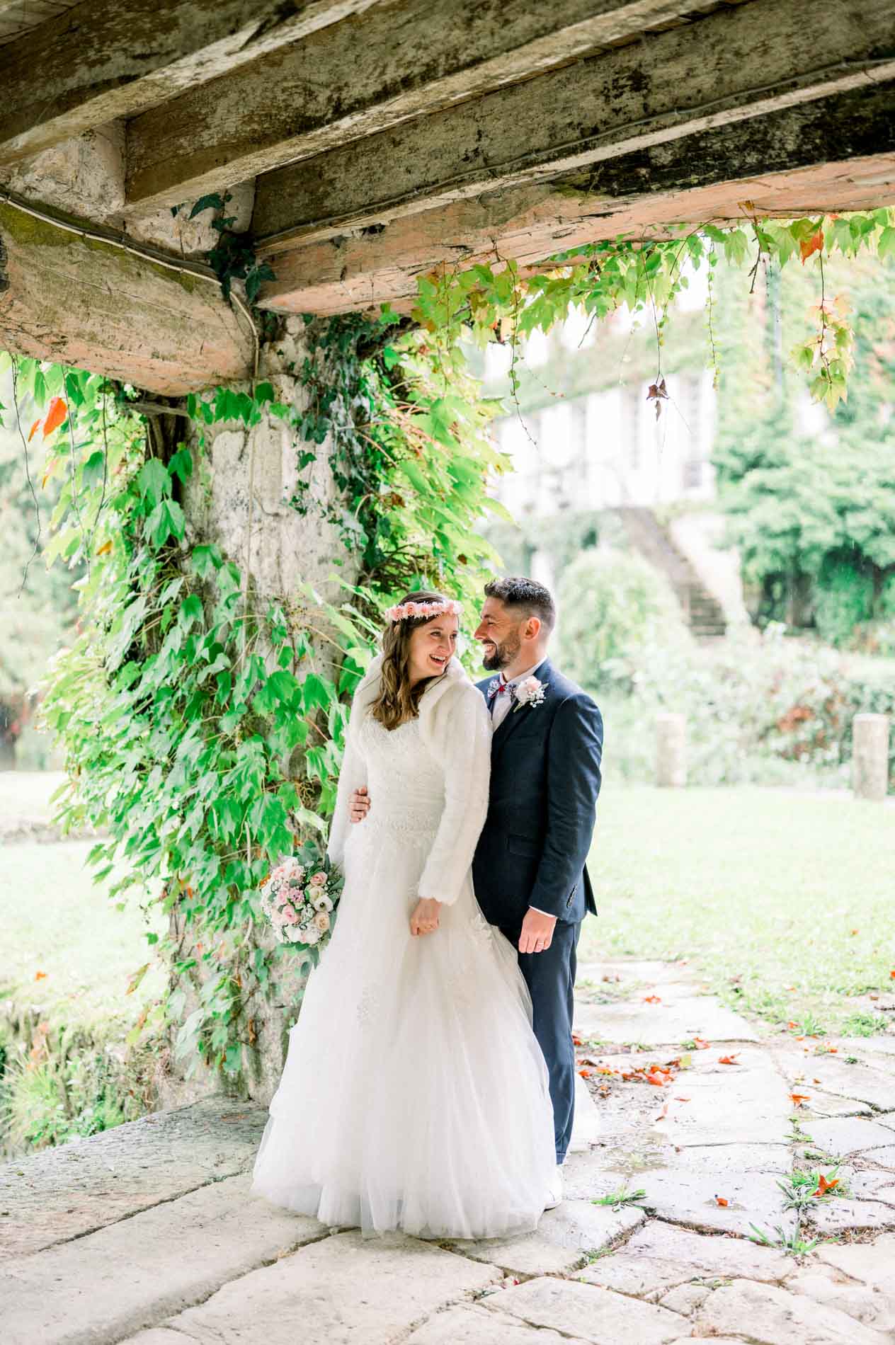 Bride and groom under an ivy-covered porch in the farmyard