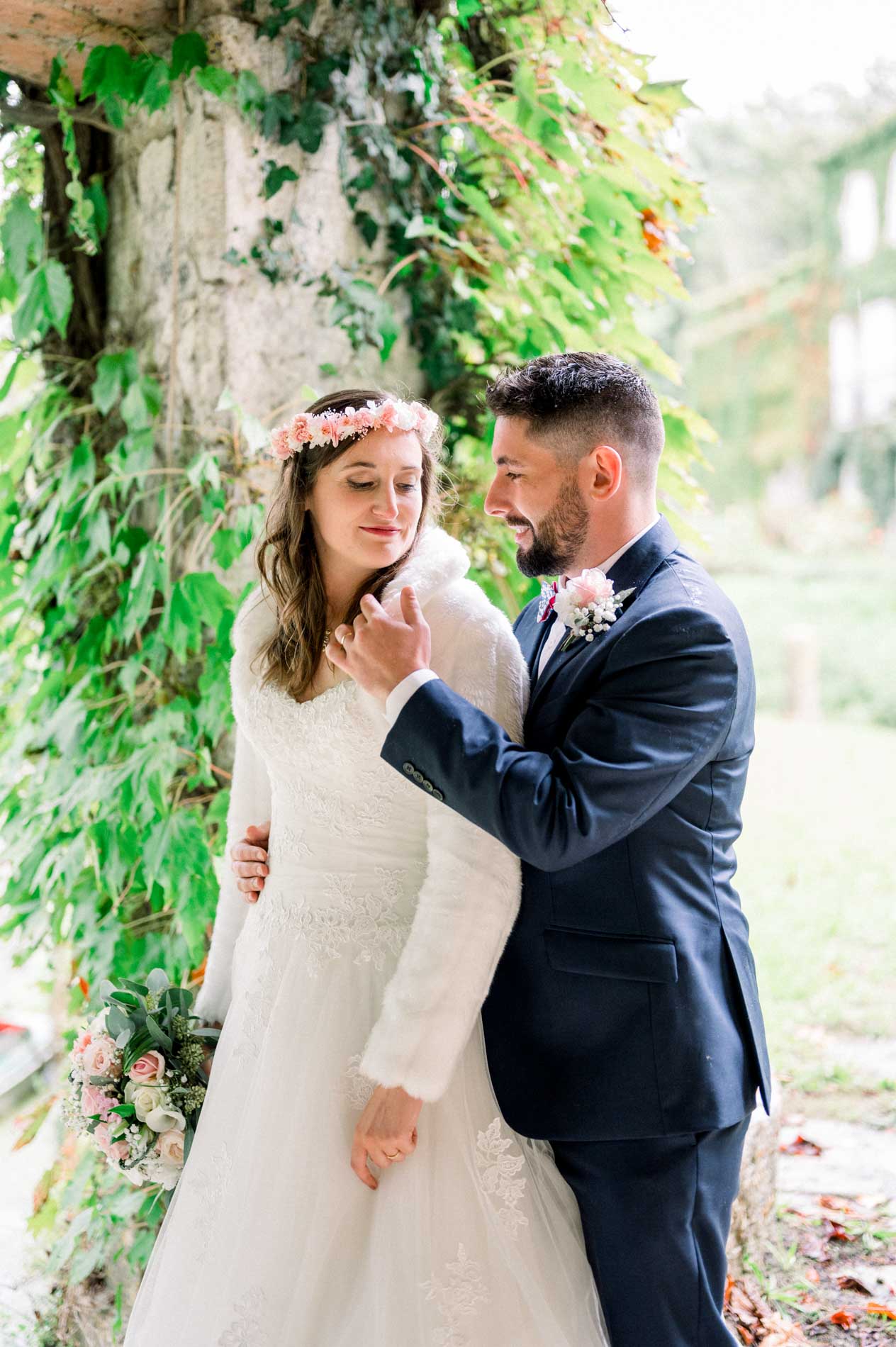 Laughing bride and groom embracing under an arch of greenery