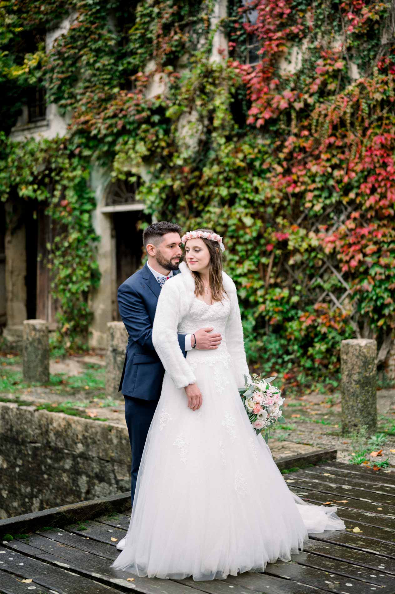 Bride and groom before a wall covered in red and green Virginia creeper