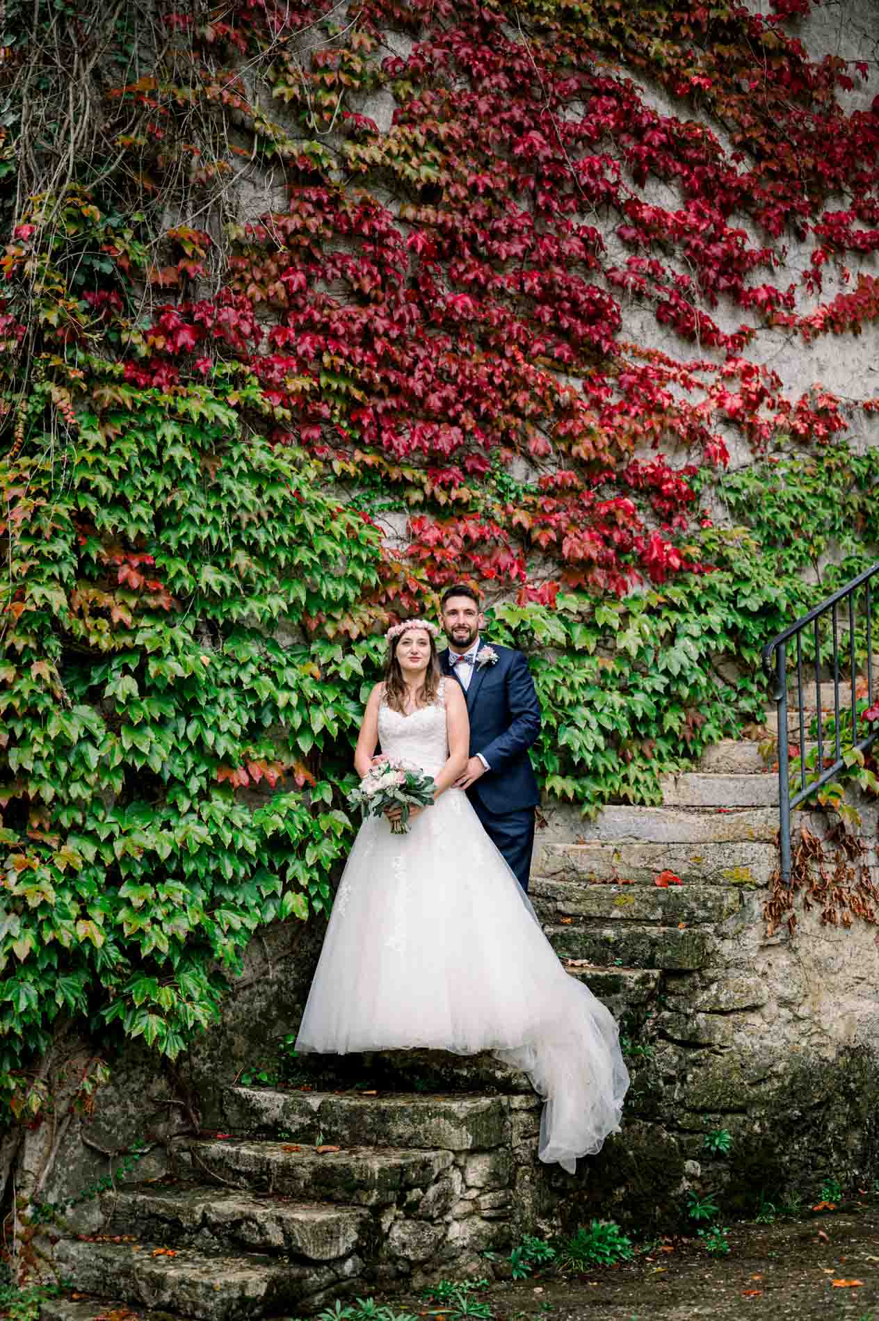 Bride and groom on stone steps framed by autumn Virginia creeper