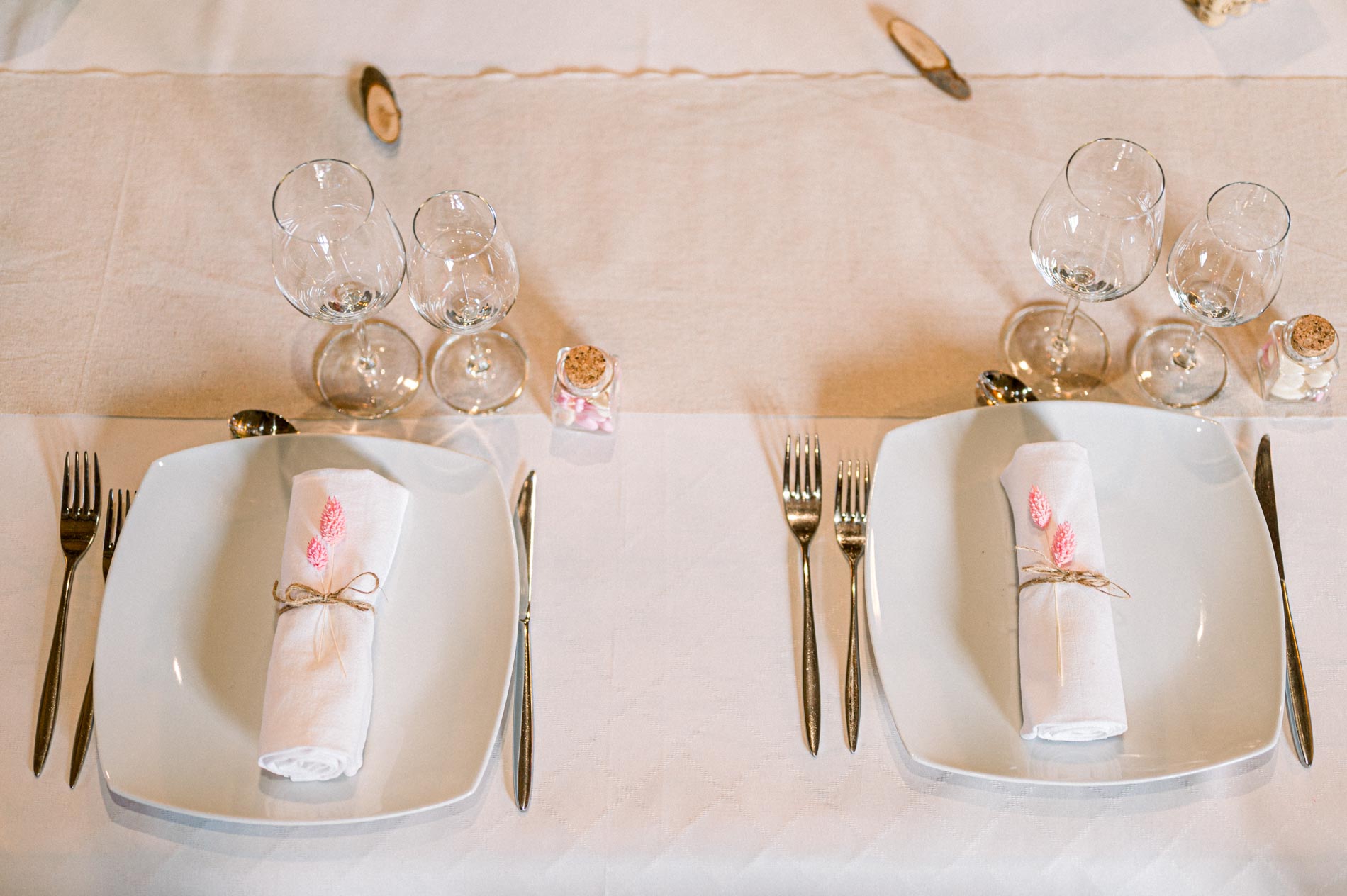 White plates and tied napkins on a linen tablecloth, seen from above