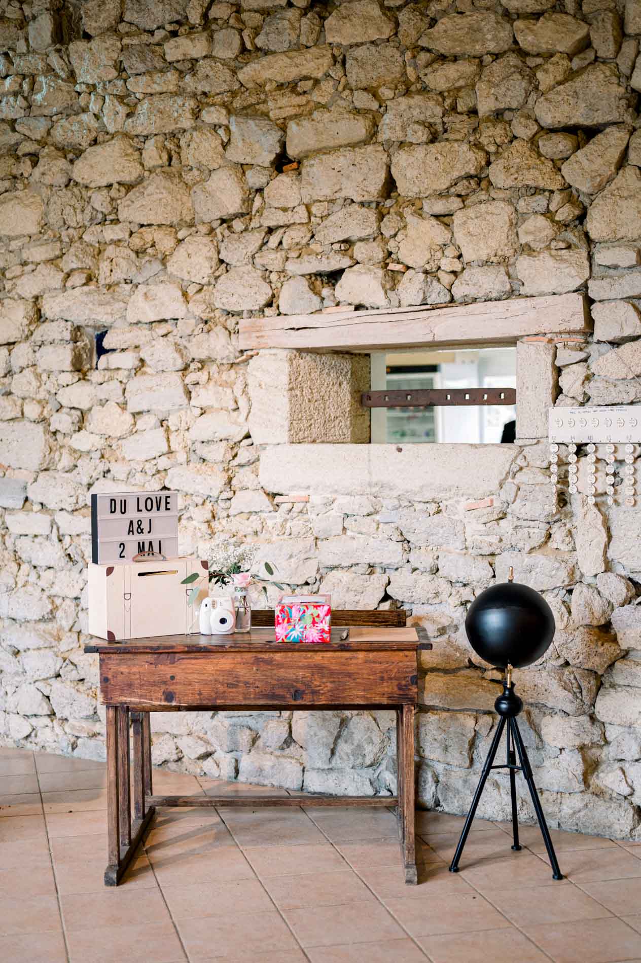 Guest book corner with an antique desk and camera against a stone wall