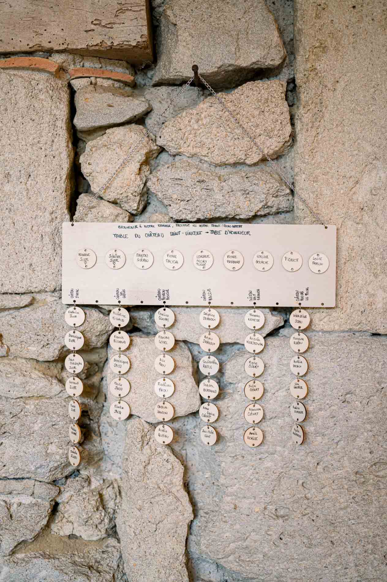 Seating chart of hanging place cards on a stone wall