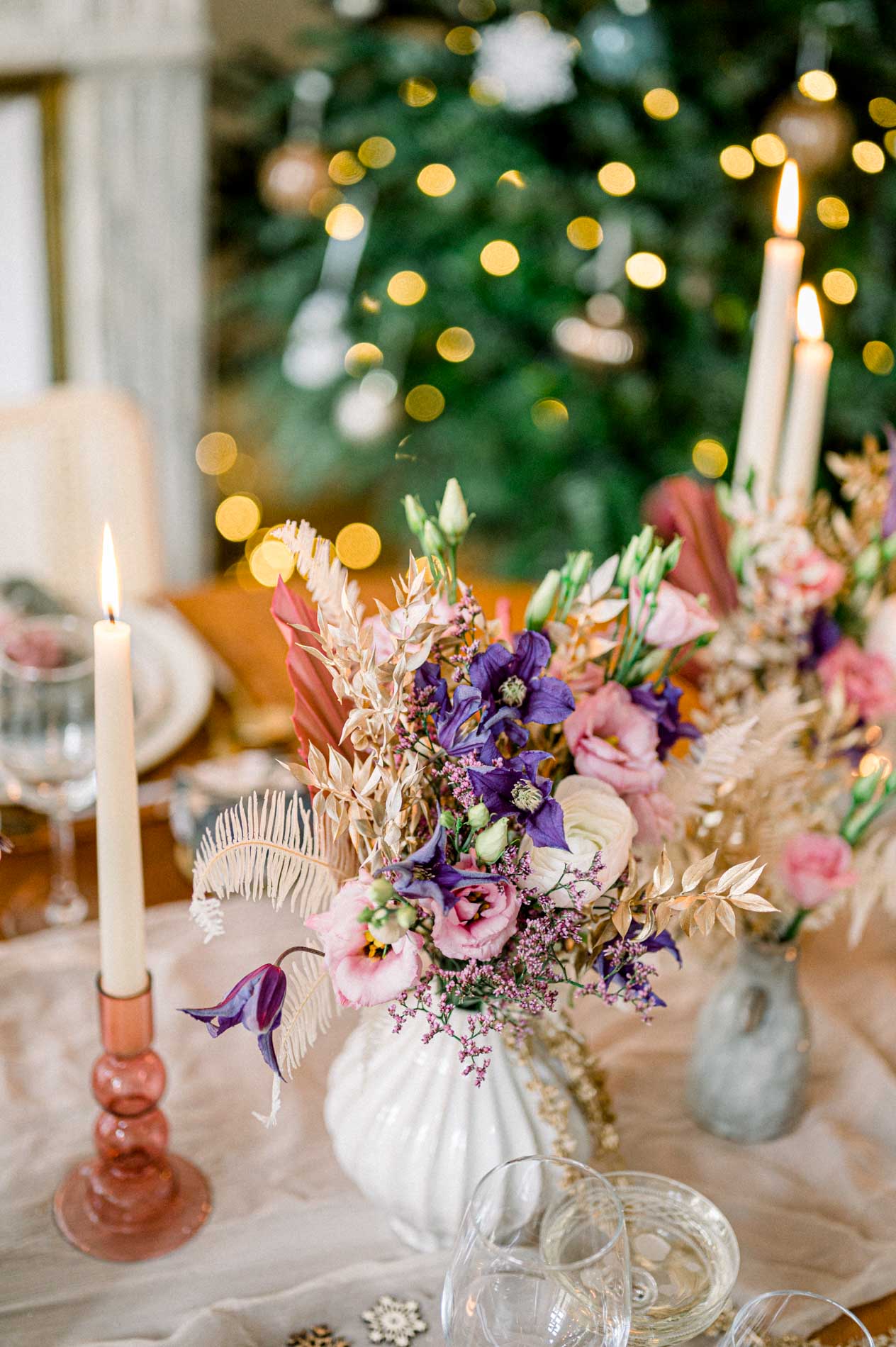 Pink and purple flower arrangement and candles in front of the lit tree