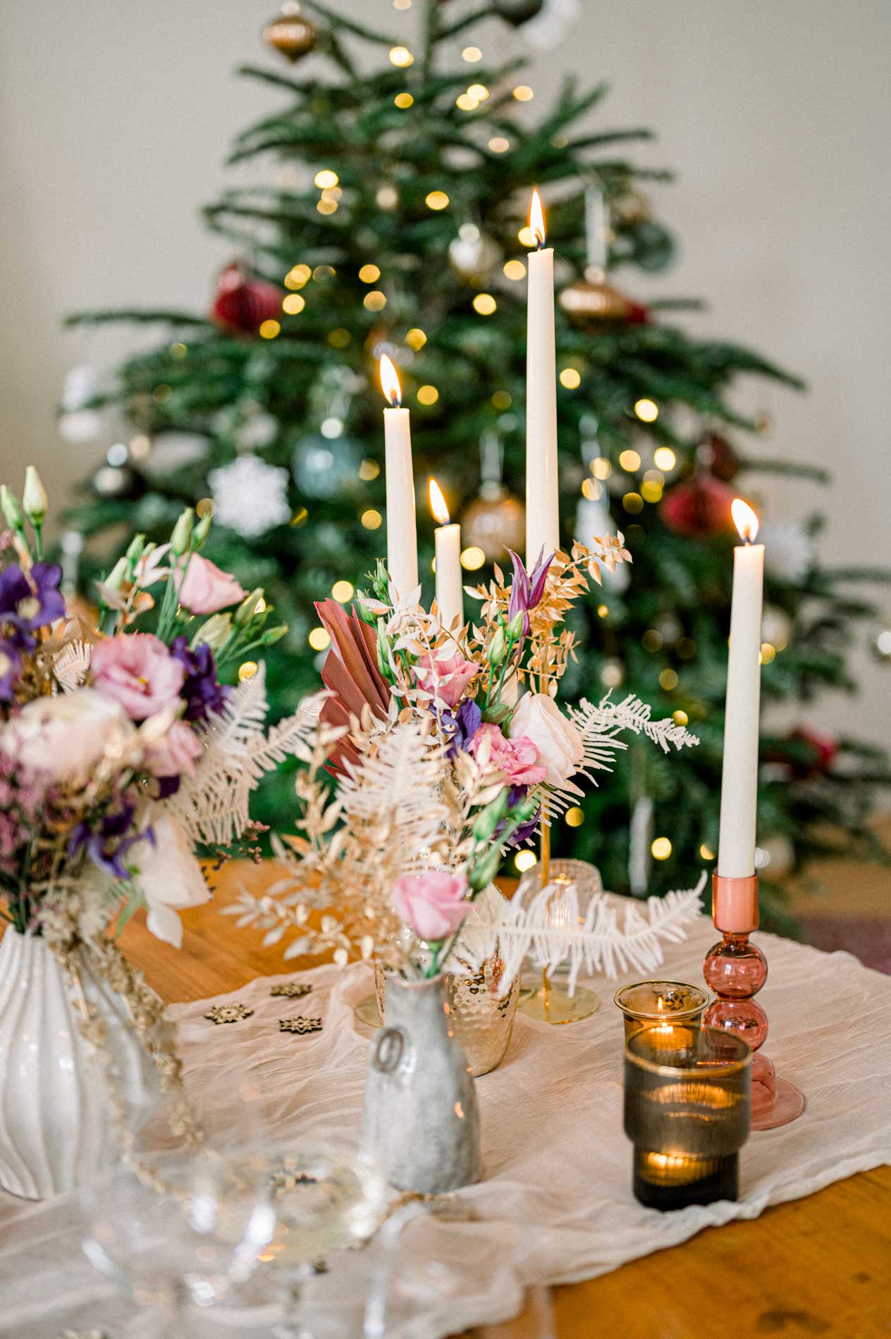 Dried flower centrepiece and white candles in front of the Christmas tree