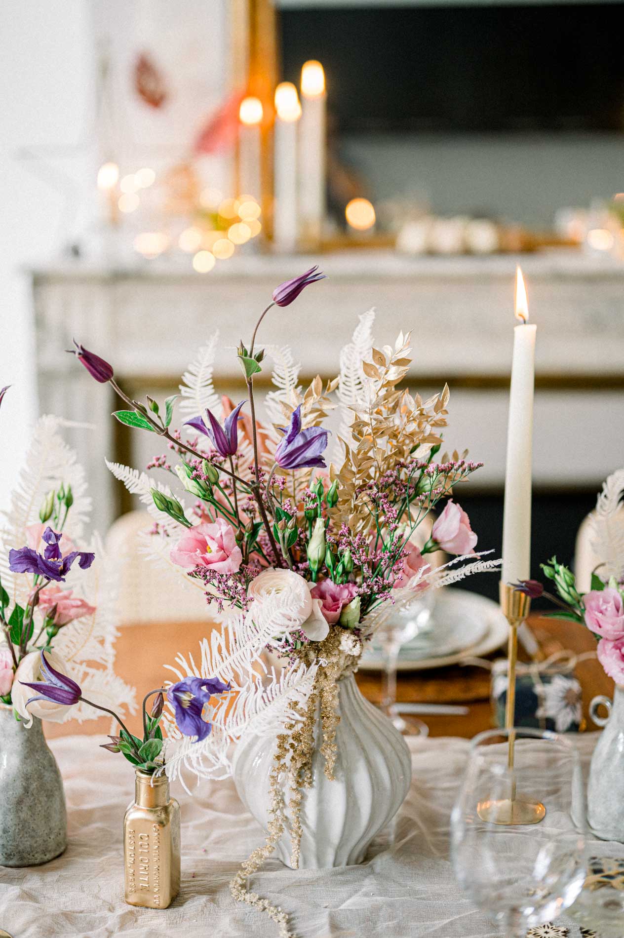 Vases of pink and purple flowers and candles on the festive table
